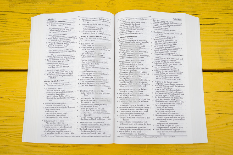 pages of an open Bible on a yellow table