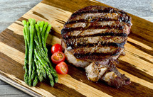 steak, asparagus, and tomatoes on a cutting board 