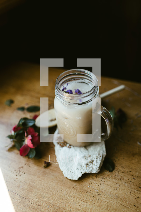 flowers, wooden spoon, glass mug, and rock