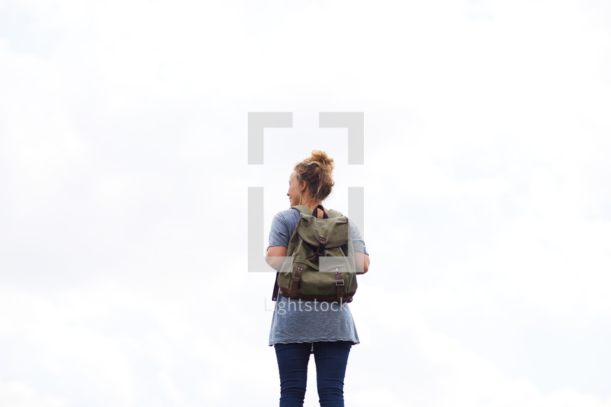 a woman with a backpack standing with her back to the camera.