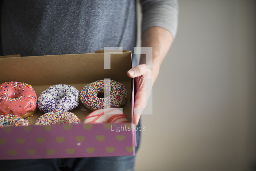 a man holding a box of donuts 