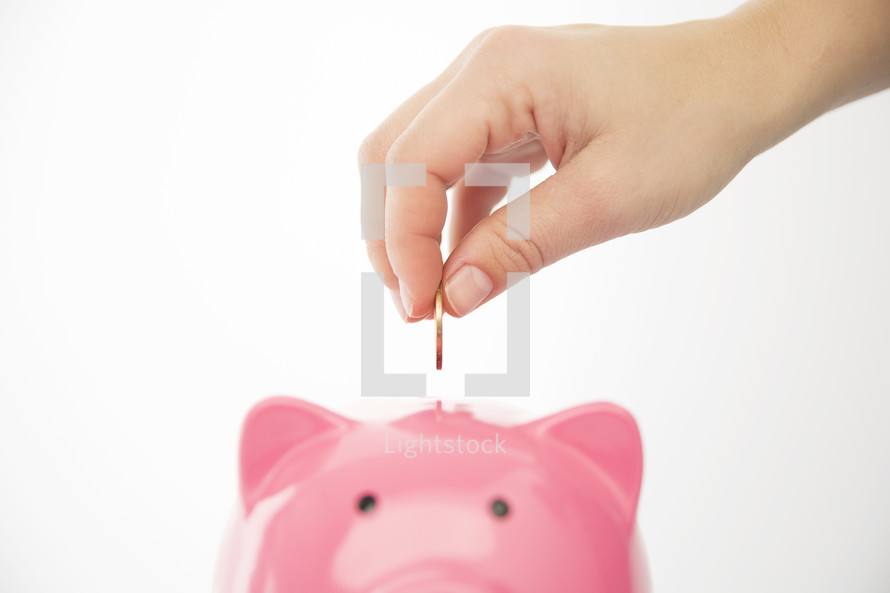 person placing a coin in a piggy bank 