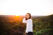 portrait of a smiling young woman standing outdoors at sunset 