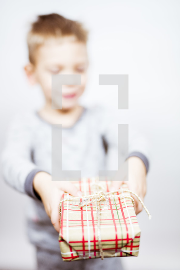 little boy in pajamas holding a present 