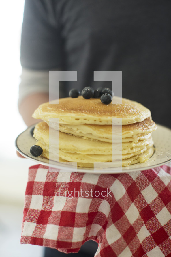 a man carrying a stack of pancakes 