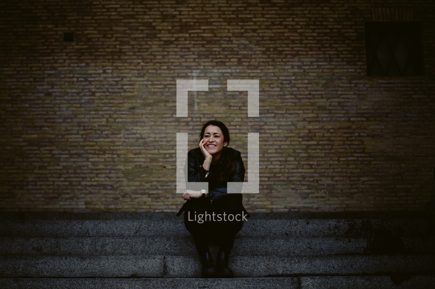 portrait of a smiling young woman sitting on steps 