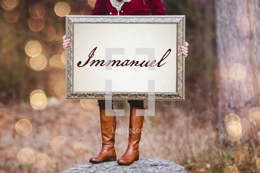 a woman holding a sign the reads Immanuel 