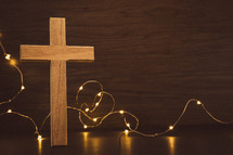 Wood cross and mini lights on a dark wood background