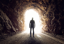 a man standing in a tunnel with light 
