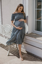 Pregnant woman in a dress by a bench