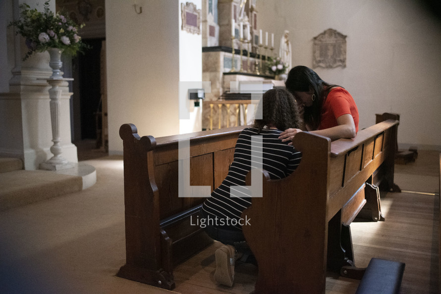 women praying together in a church pew 