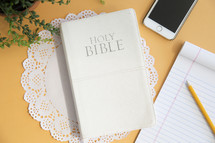 yellow background, Bible, house plant, doilies, pencil, notepad, morning devotional, table, cellphone 