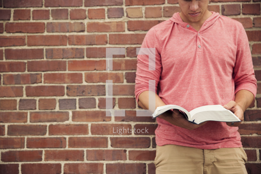 man looking down reading a Bible 