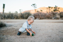 a toddler playing with a toy car and desert landscape 