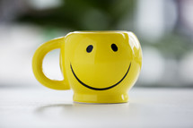 smiley face coffee mug on a table.