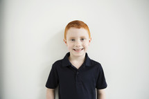 A smiling red haired boy.