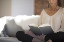 a woman sitting on a couch reading a book 