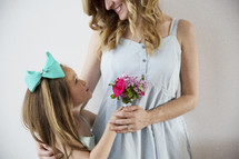 A young girl giving her mother a bouquet of flowers.