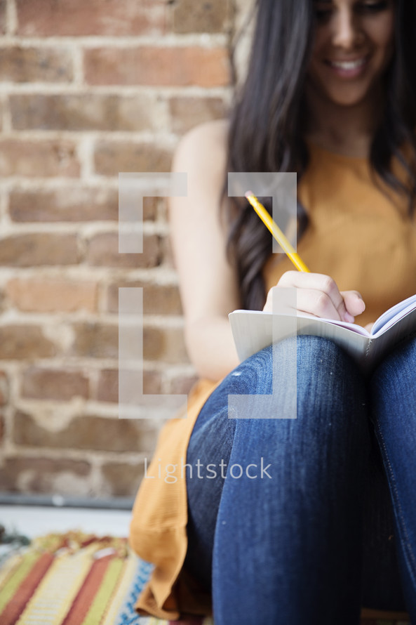 A young woman writing in a journal.