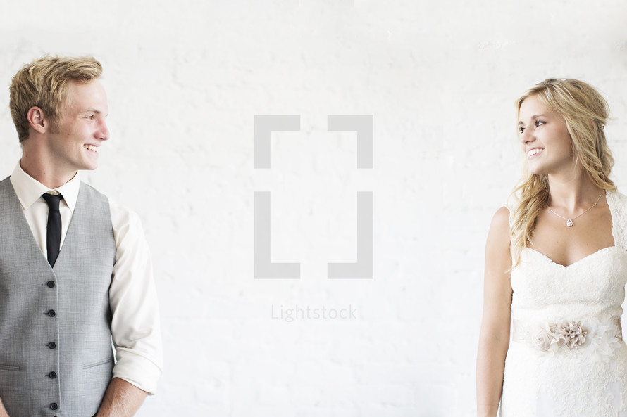 portrait of a bride and groom smiling at one another. 