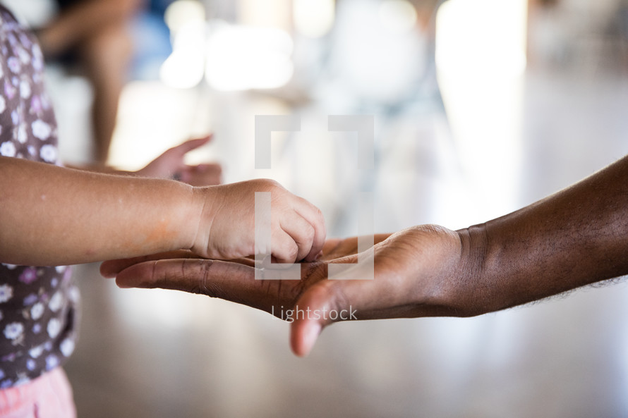 a child's hand touching an adult's hand