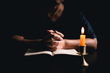 Bible and candlelight with praying hands