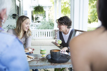 women sitting at an outdoor table talking.