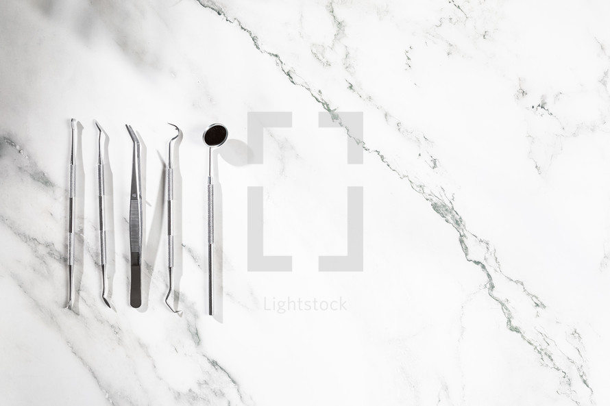 Dental instrument and flat layer on marble background