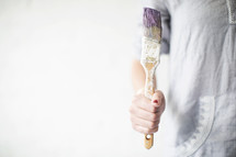 A paint brush being held by a woman.