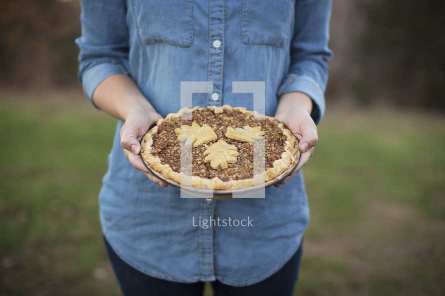 A woman standing and holding a freshly baked pie.