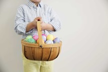 a child holding an Easter basket full of colorful eggs.