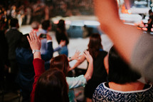 people with hands raised at a worship service 
