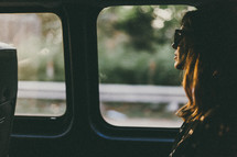 a woman riding in the back of a van looking out a window 