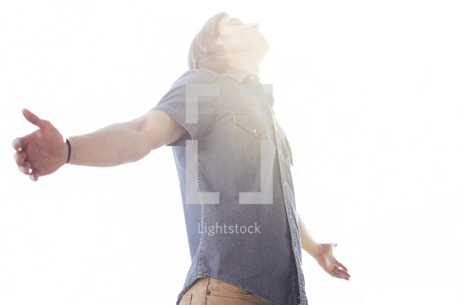 a man standing with outstretched arms enjoying the sunshine.