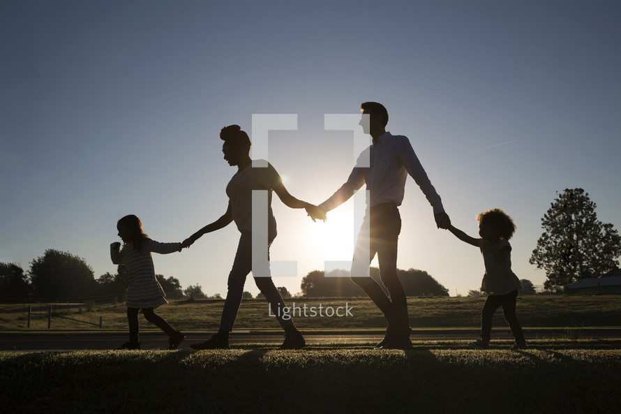 a family walking holding hands down a sidewalk 