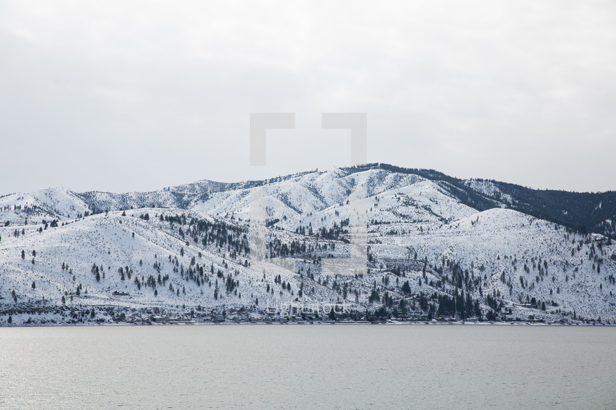 snow on a mountains beside a lake 