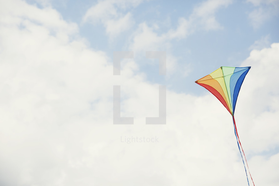 a rainbow colored kite in the sky.