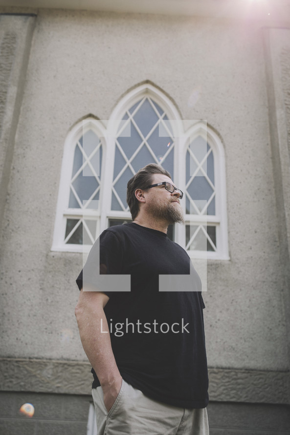 a casual pastor in front of church window