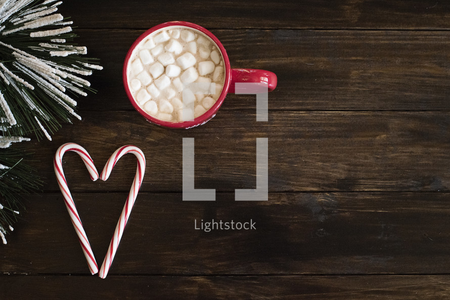 marshmallows and hot cocoa in a red mug and candy canes in the shape of a heart 