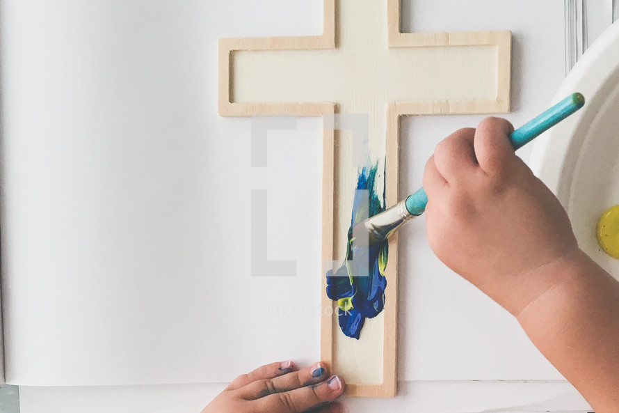 a toddler painting a cross with a stencil 