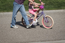 a father teaching his daughter to ride a bike