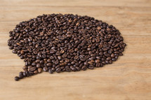 Coffee beans in a balloon formation on a wood table.