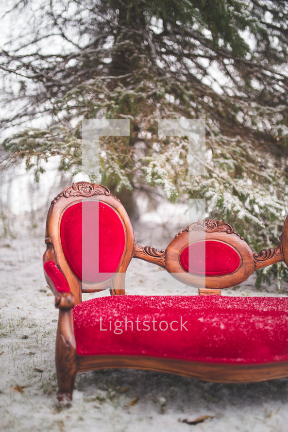 a red couch outdoors in the snow 