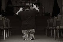 man kneeling on his knees in the aisle of a church