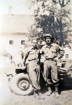 A vintage photograph taken around 1940 - 1944 of two American I soldiers photographed in front of an army jeep while stationed in Normandy, France during World War 2.  