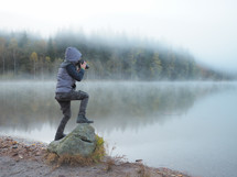 boy taking pictures of a lake with a camera 