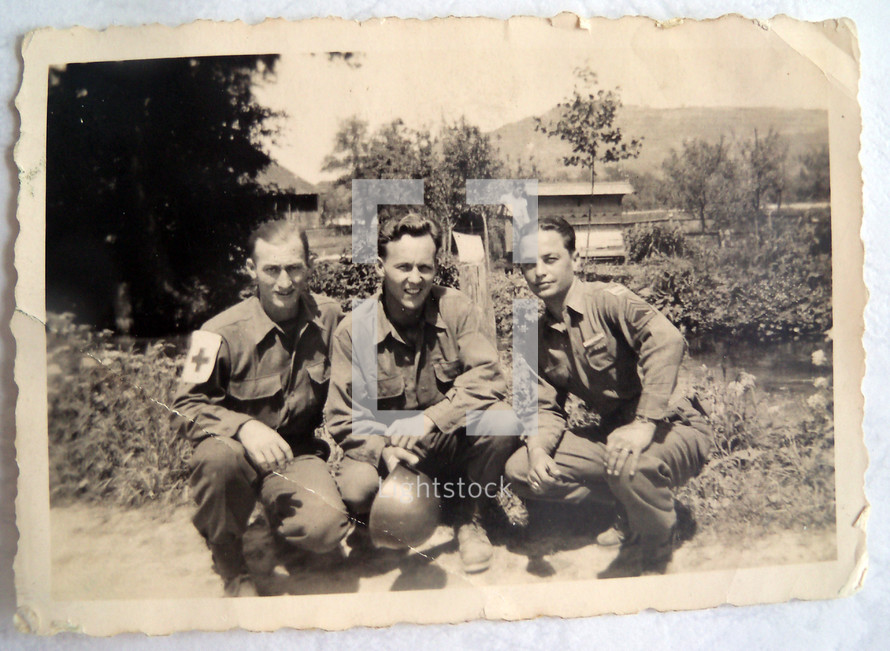 A vintage photograph of three US Army Soldiers including an Army Medic and his two pals stationed over in Normandy, France during World War II around 1942- 1944.  