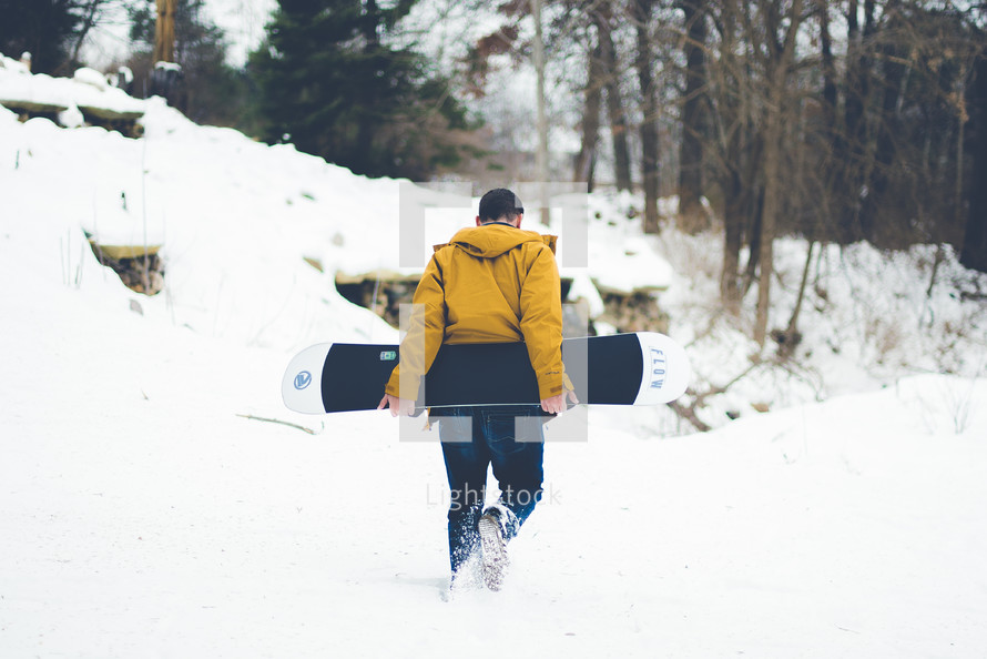 a man walking with a snowboard 