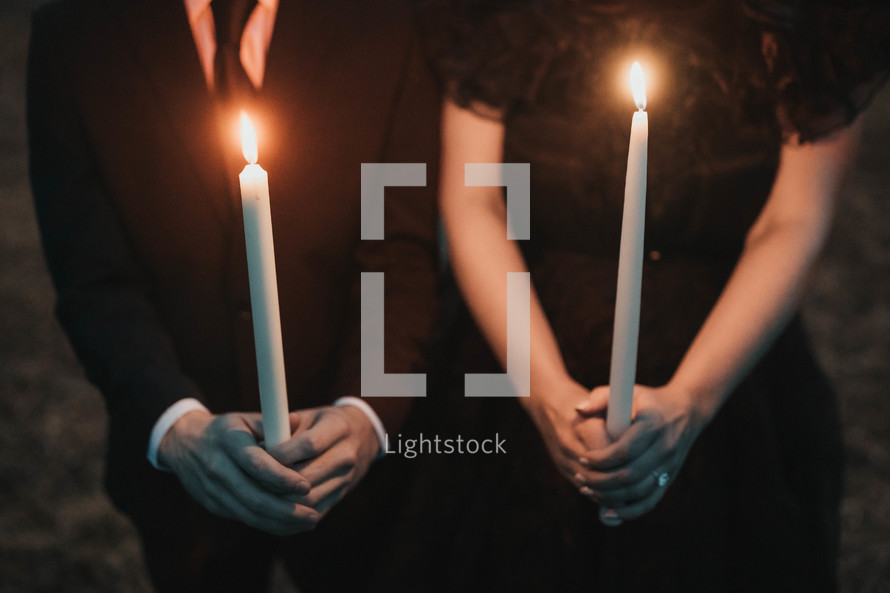 couple dressed in black holding candles