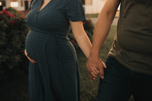 a pregnant woman and her husband hold hands